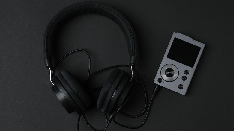 A digital audio player connected to headphones against a dark background.