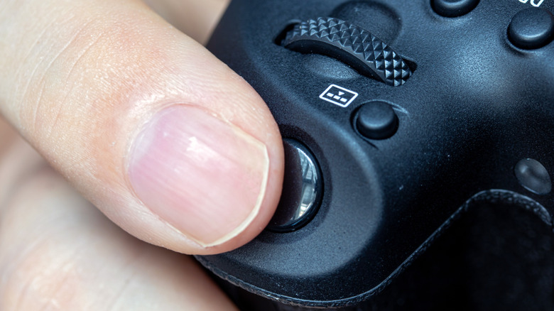 Someone pressing the individual shutter button on a digital camera.