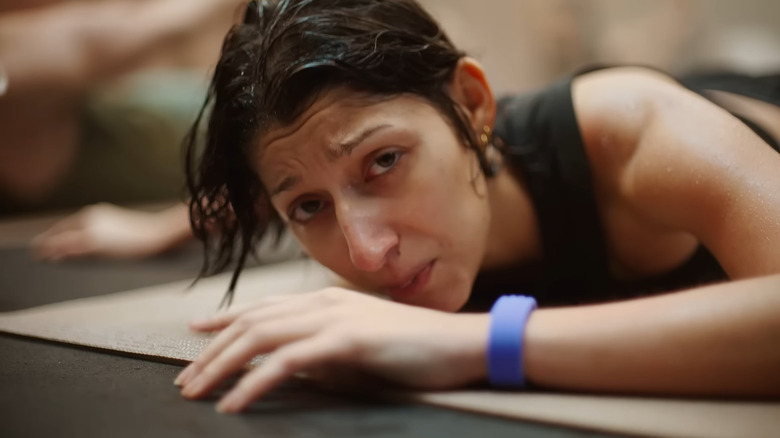 A person looking mildly disgruntled lying on a yoga mat and wearing a purple Fitbit Air on their wrist.