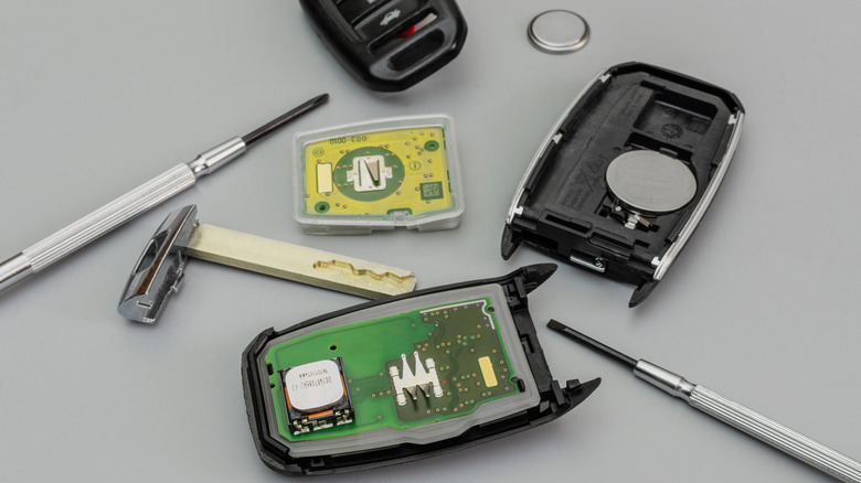 Close up view of a key fob taken apart with tools and battery visible.