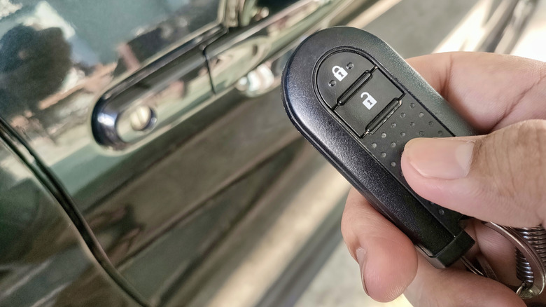 Someone using a key fob to unlock their car door.