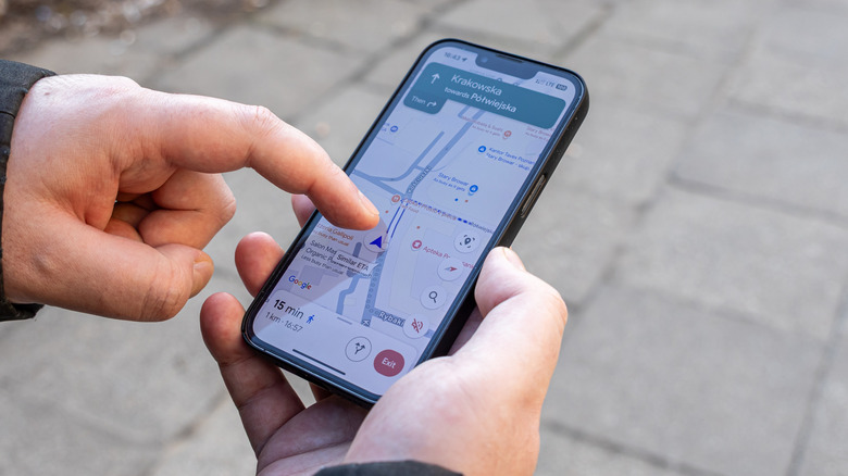 A man holding a phone with Google Maps on screen.