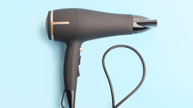 A black hairdryer on a blue background.