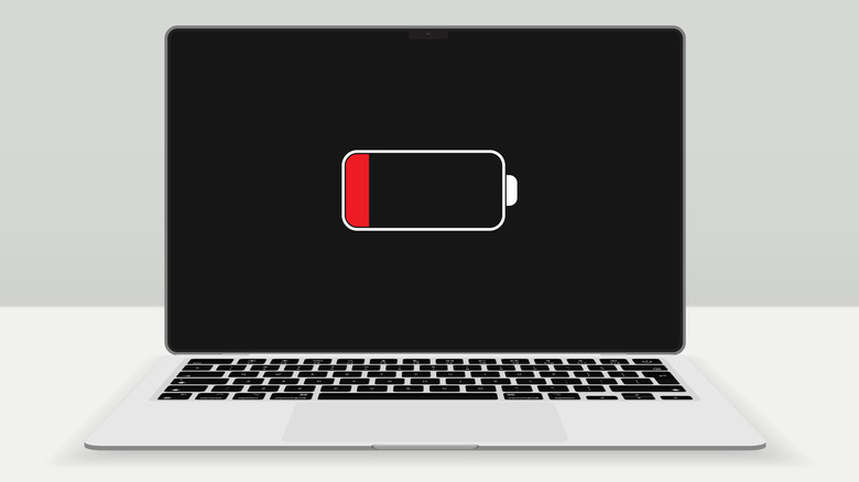a laptop on a white surface that show low battery symbol on the screen
