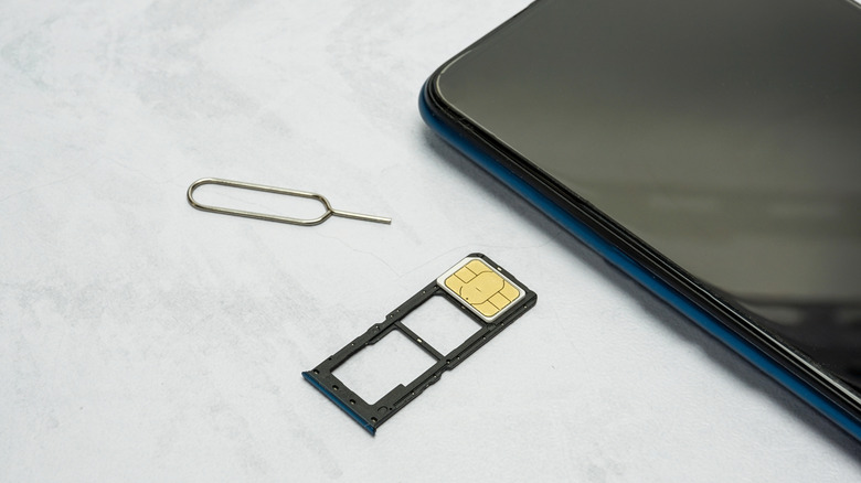 A smartphone with a physical SIM card tray next to it.