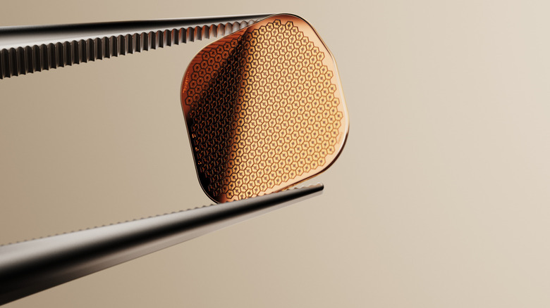PRIMA ocular implant held by tweezers up close.