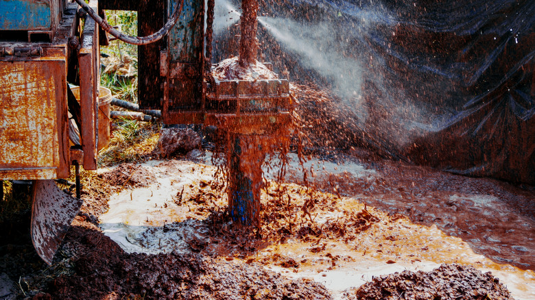 a muddy groundwater drill with water spraying out