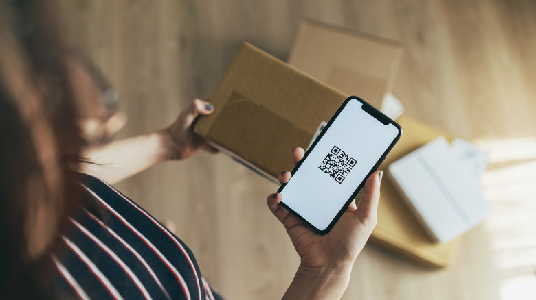 A person scanning a QR code on a package.