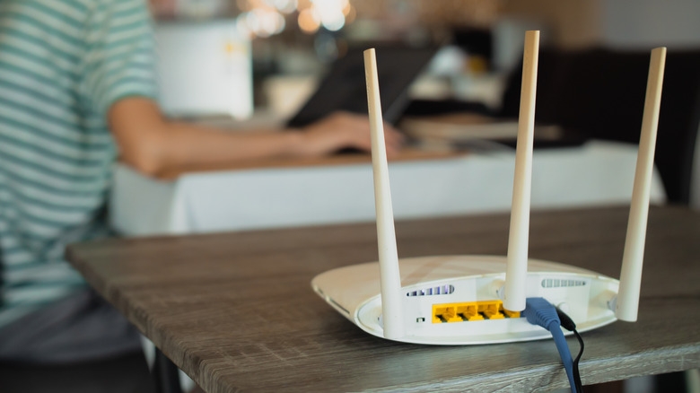 A wi-fi router on a table with a person in the background