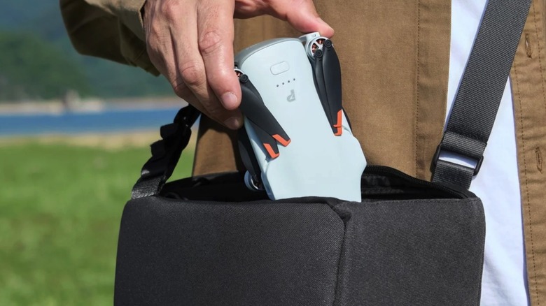 A person placing the folded Potensic Atom 3 drone in a black bag.