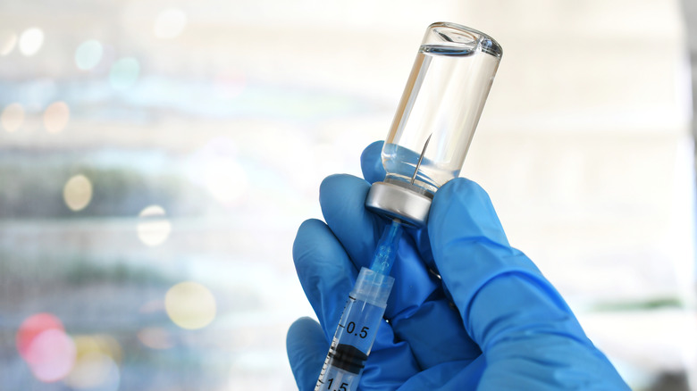 Doctor filling hypodermic needle with vaccine