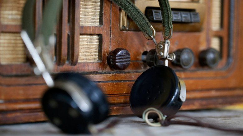 Antique headphones with radio equipment in the background.