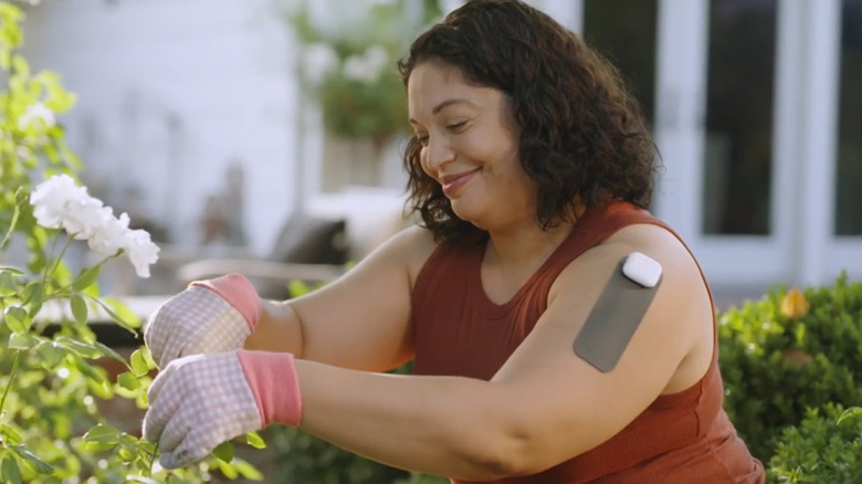 Woman wearing Hinge Health's Enso health tech wearable on her shoulder while gardening