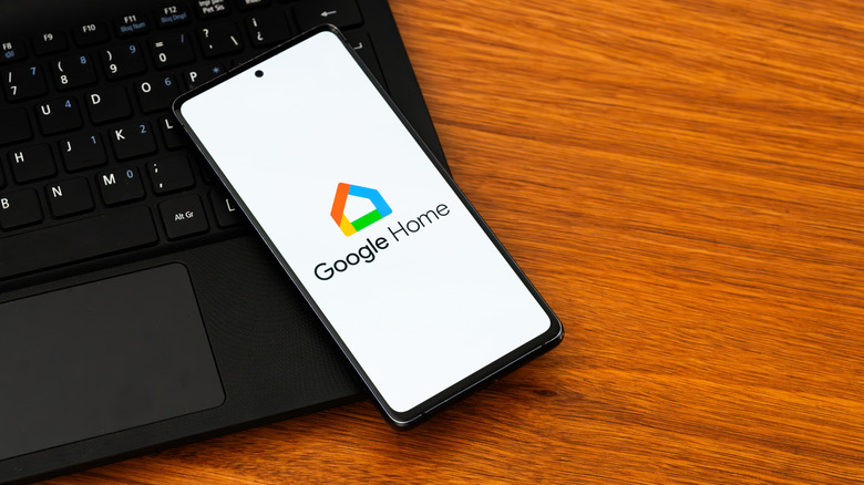 A smartphone displaying the Google Home app logo, on top of an open laptop