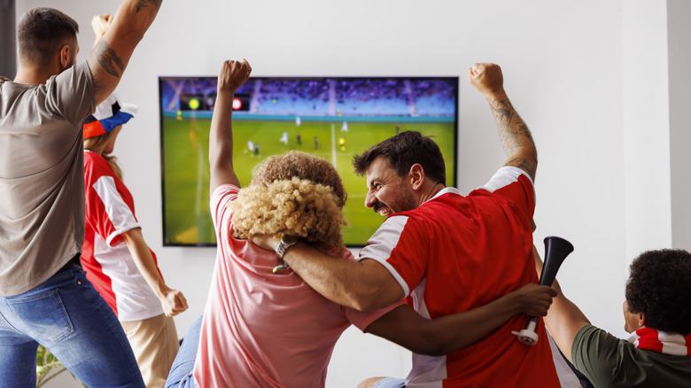 People cheering at the TV during a Super Bowl party