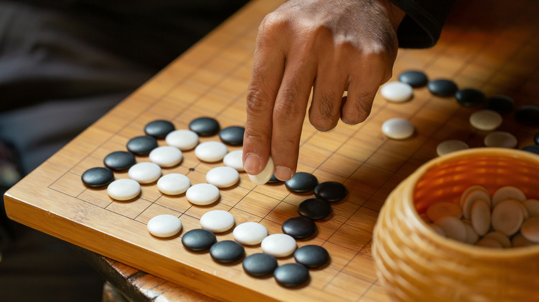 Hand placing Go stones on board