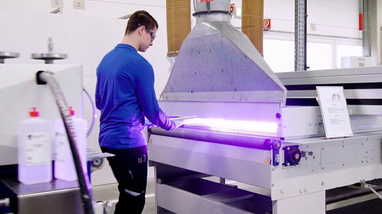 Man using UV machine to create coating for wood furniture