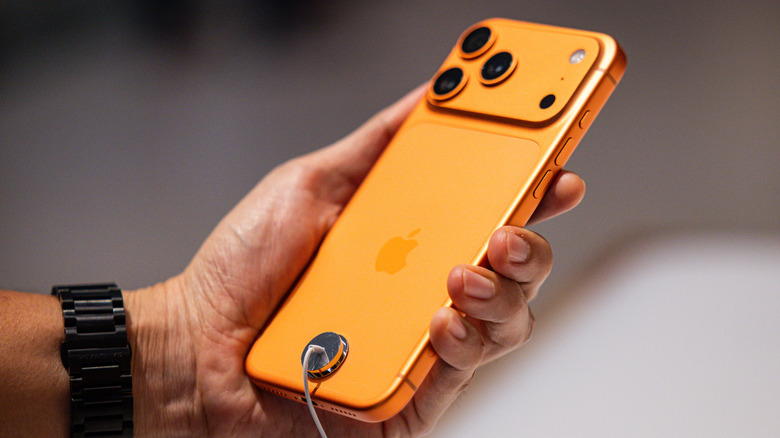 The iPhone 17 Pro Max in Cosmic Orange held in the hand