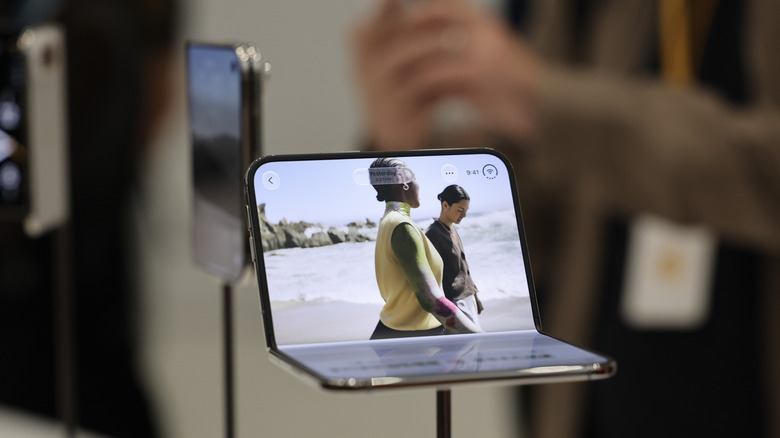 close-up iPhone duo on display showing video footage on one screen while only halfway unfolded