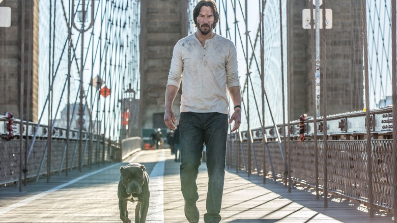 John Wick (Keanu Reeves) walking across a bridge with his dog