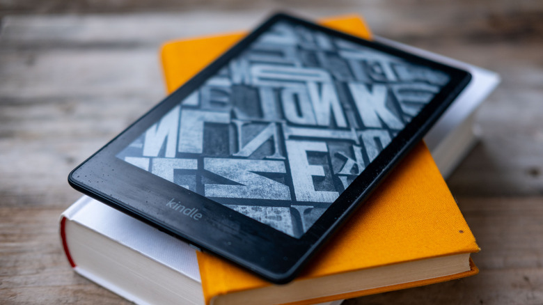 A Kindle sitting on top of a stack of books.