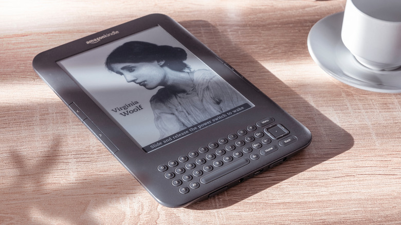 Kindle Keyboard on wooden desk with a white cup and saucer beside it