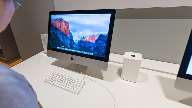 Person using Mac with AirPort tower next to it