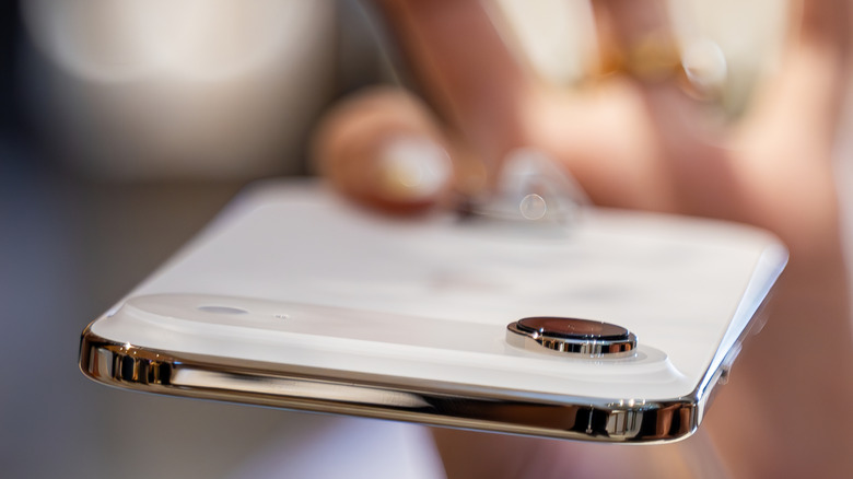 A hand pinches the bottom of an iPhone Air, emphasizing its thinness.