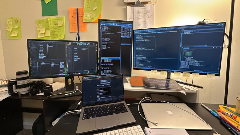A desk setup with three monitors powered by a MacBook
