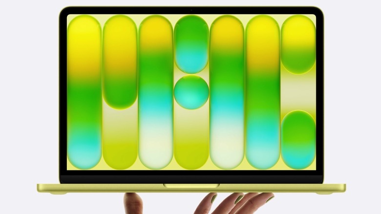 MacBook Neo in Citrus held in hand.