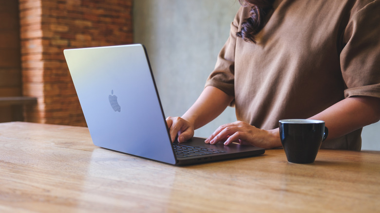 A closeup of a user with both bands on a black MacBook, the image is cropped so that the user's head cannot be seen
