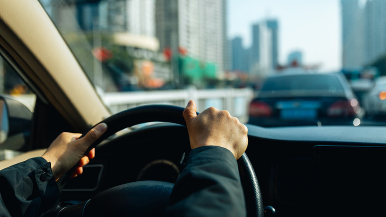 a view out of a car front window as someone drives on the road in a city