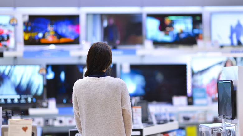 woman looking at wall of TVs in store