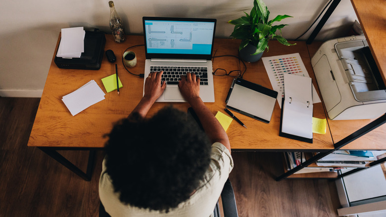 A woman working from home with a printer next to her