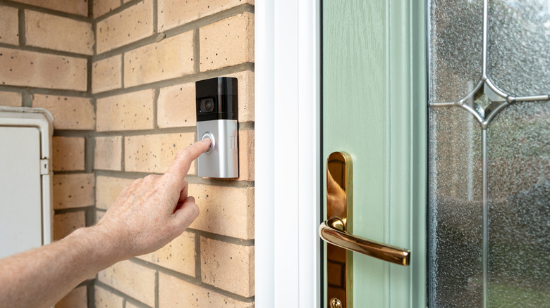 Visitor seen pressing the door bell button of a smart home door bell