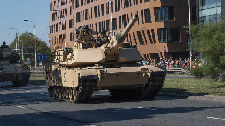 M1 Abrams tanks rolling down a modern street.