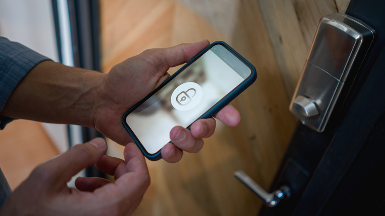 a person holding a phone with a lock symbol on it near a door lock