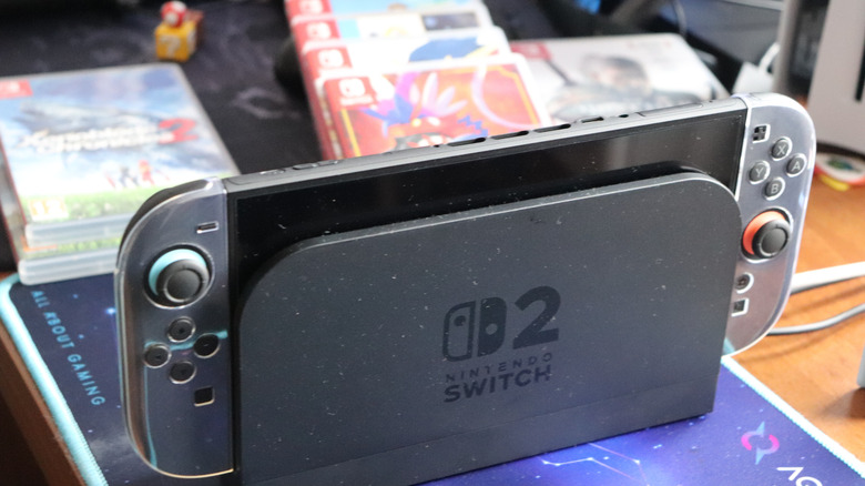 Switch 2 sitting on a desk with games visible behind it