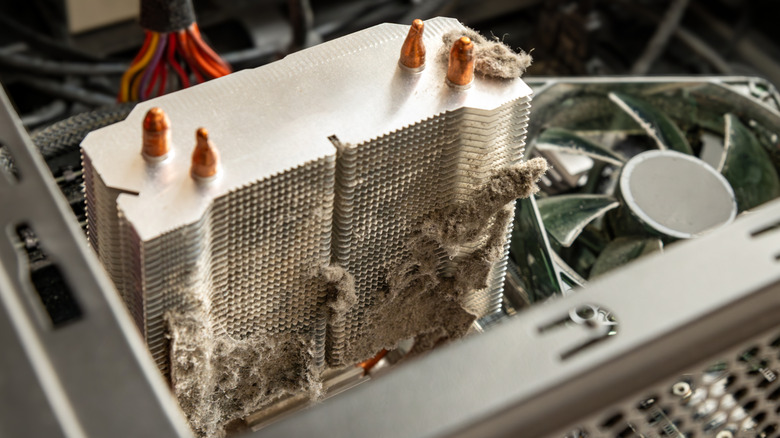 Dust-covered CPU air cooler and PC fan inside desktop computer case