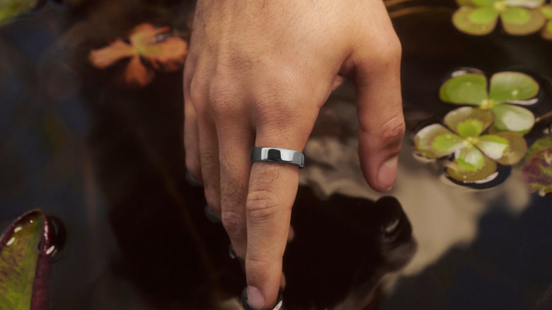 An Oura Ring 5 worn on a person's index finger