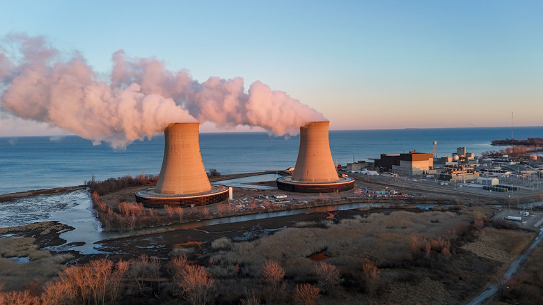 A nuclear power plant emitting white smoke near a sea shore
