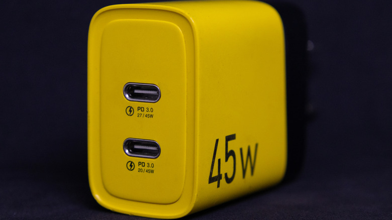 A charger with a bright yellow design has two USB-C ports for quick charging of various electronic devices. It is shown against a dark background.