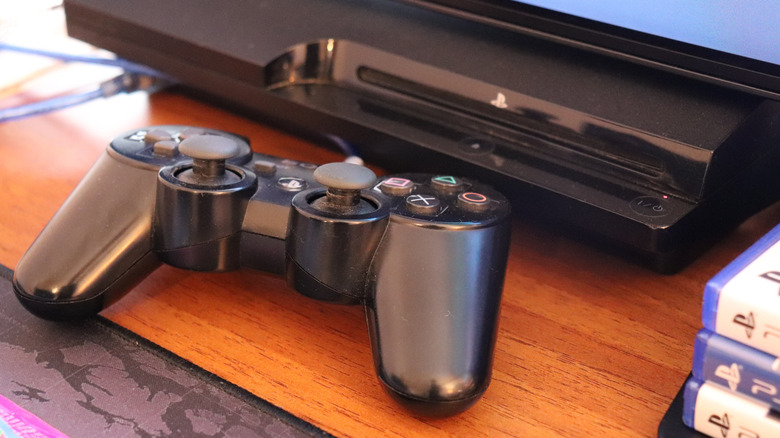 PlayStation 3 console under TV with controller and games nearby
