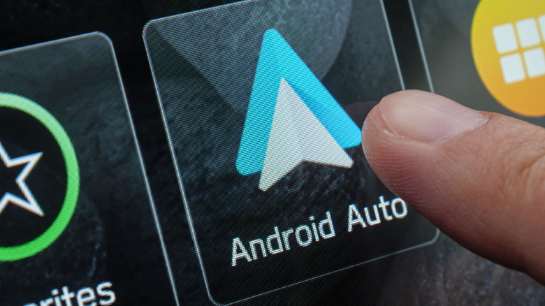 a finger tapping the Android Auto app on a phone