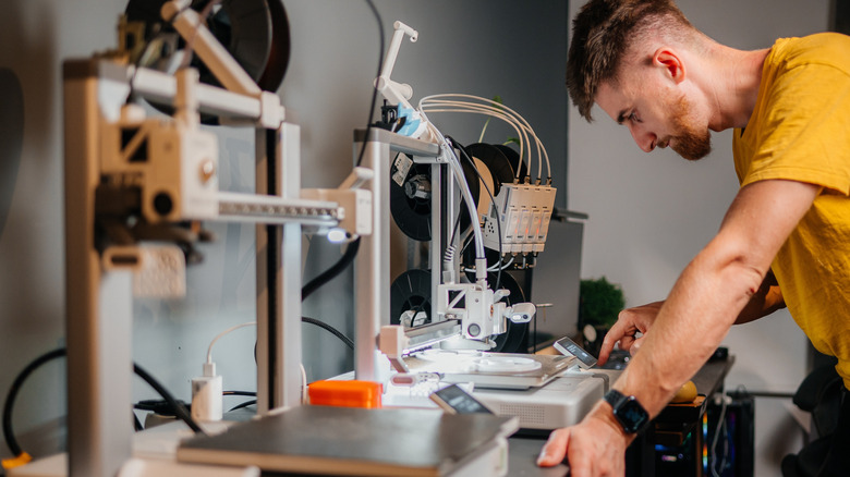 Man looking at different types of 3D printers