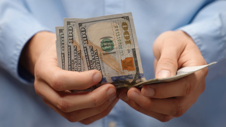 Close-up of hands counting hundred dollar bills