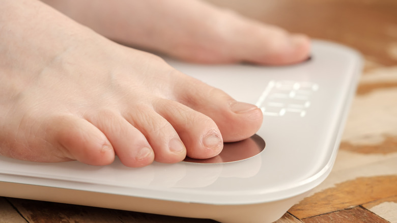 Someone using a smart scale showing weight.