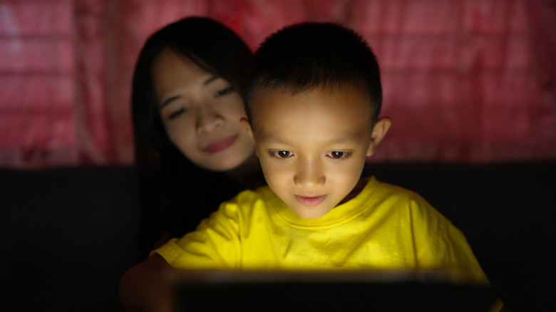 A child and mother looking at a bright screen