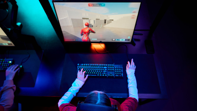 A gamer using a mouse and keyboard to play a fast-paced game on an OLED monitor