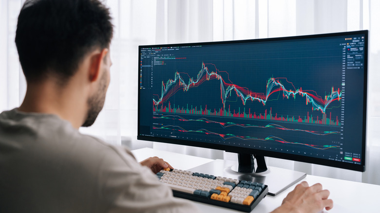 A man works at a curved monitor with a graph on the screen